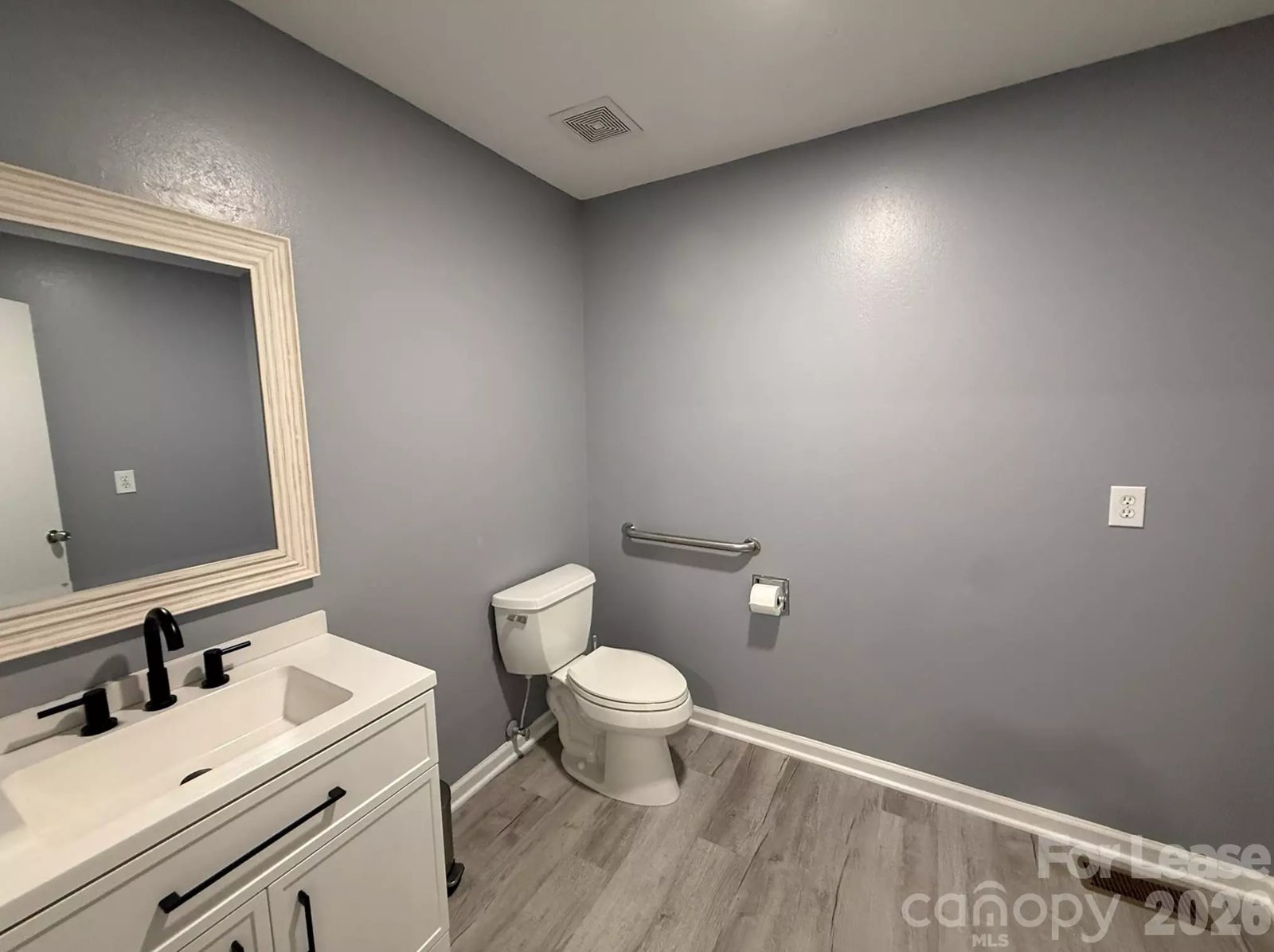 Renovated accessible restroom with grab bar shared by office tenants
